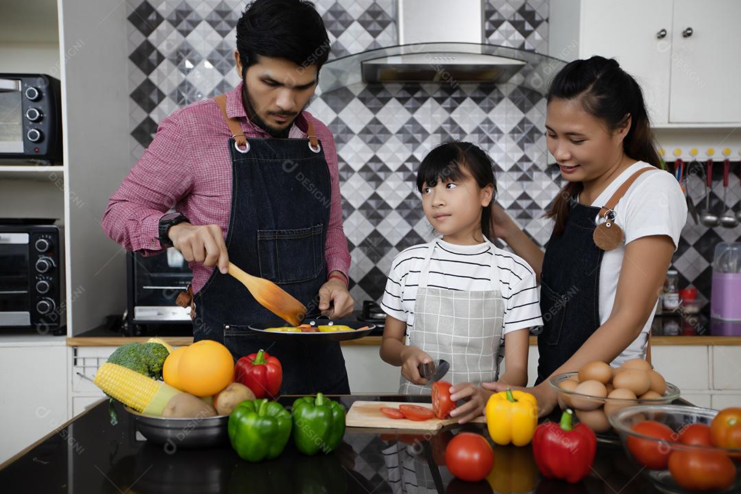 Família feliz tem papai, mamãe e sua filhinha cozinhando juntos na cozinha