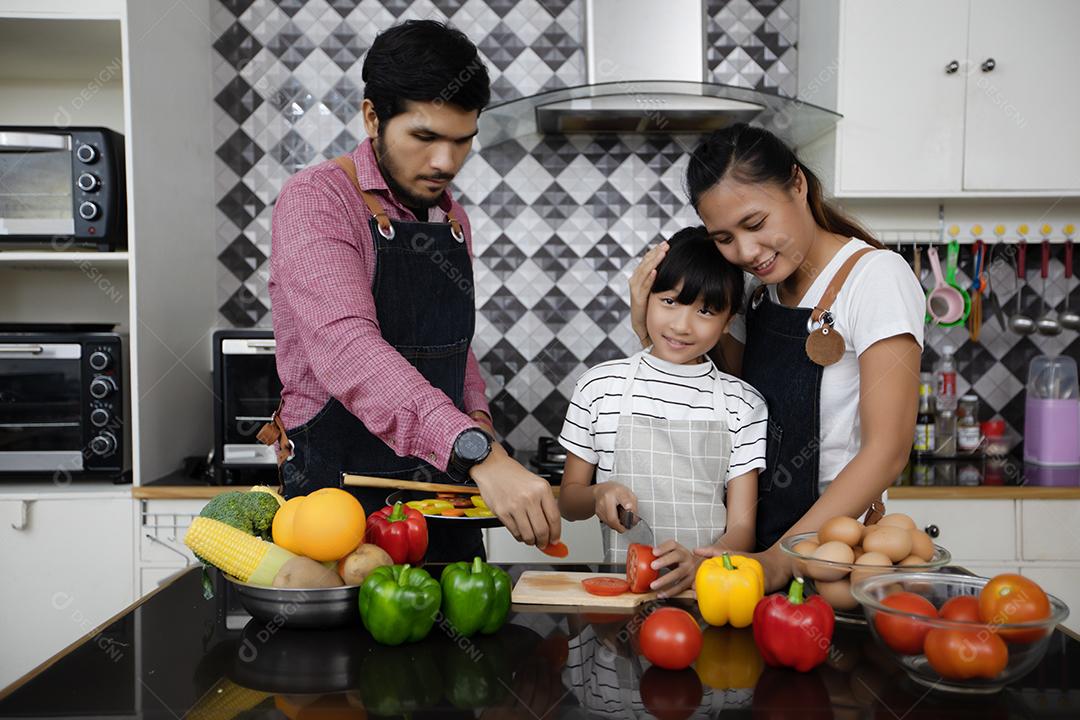 Família feliz tem papai, mamãe e sua filhinha cozinhando juntos na cozinha