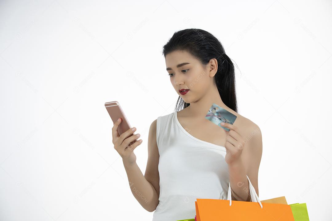 Mulheres asiáticas e linda garota estão segurando sacolas de compras e usando um telefone inteligente e sorrindo enquanto fazem compras e compram com cartão de crédito