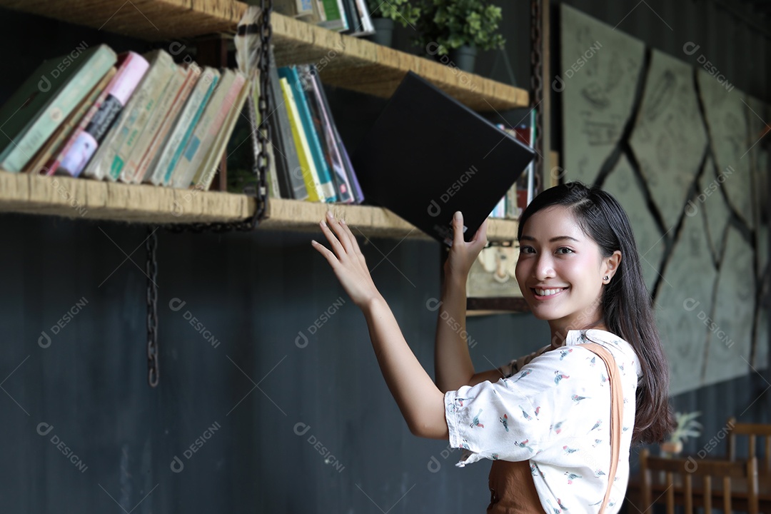 Alunas asiáticas segurando para seção na estante de livros