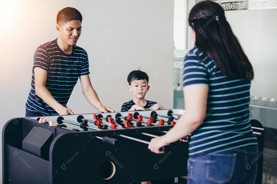 Família feliz jogando futebol de mesa para relaxar nas férias em casa