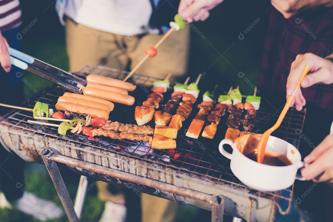 Grupo asiático de amigos fazendo churrasco no jardim ao ar livre rindo
