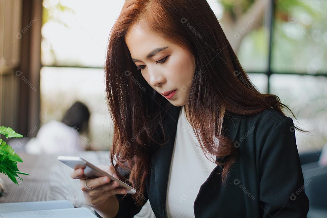 Empresários e mulheres estão usando telefone inteligente móvel e sensível ao toque para comunicação e verificando pessoas de negócios no fundo do escritório