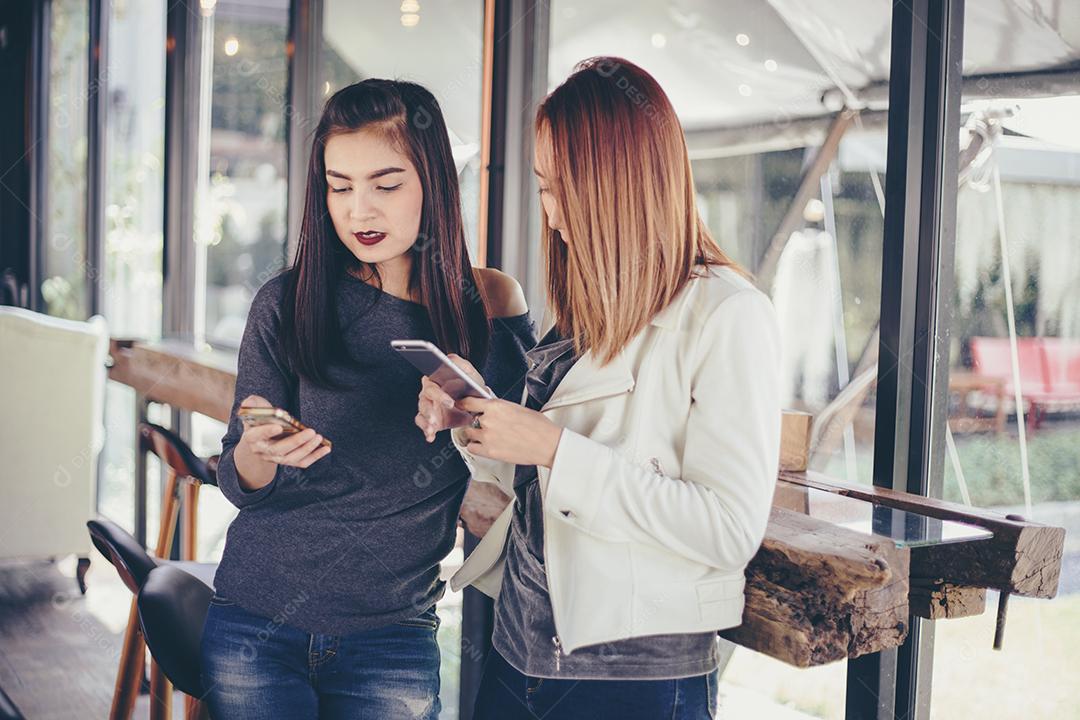 Jovem olhando para o telefone de sua amiga e se sentindo excitante e sorrindo enquanto está sentado na sala de estar no escritório