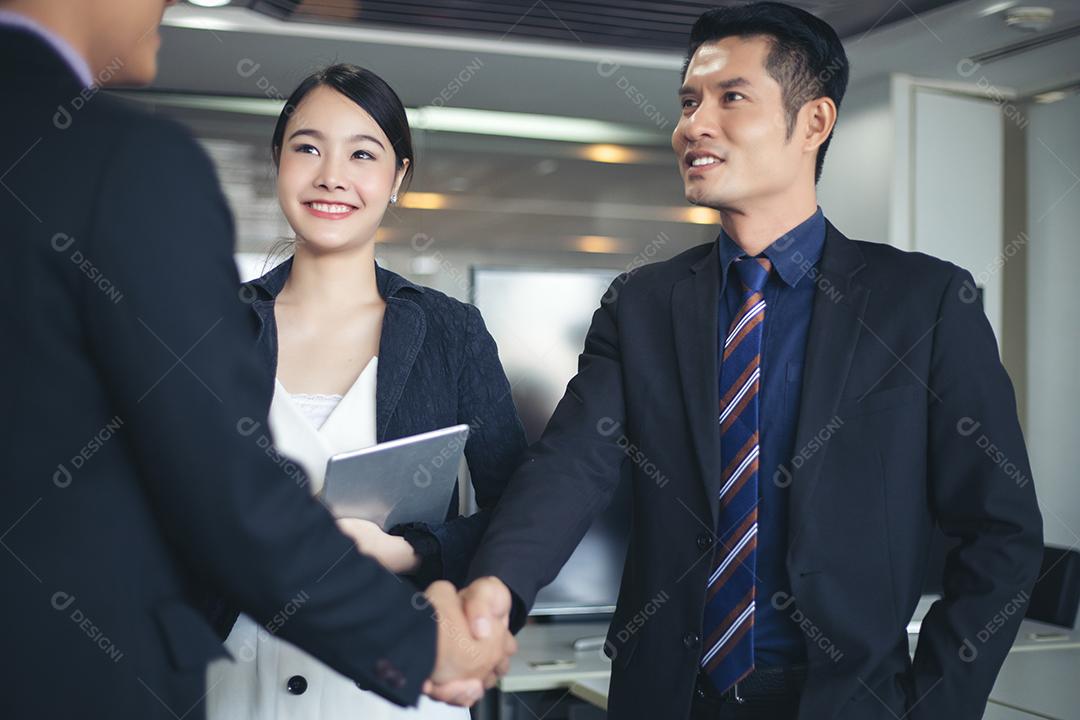 Empresários apertando as mãos e sorrindo seu acordo para assinar contrato e terminar uma reunião