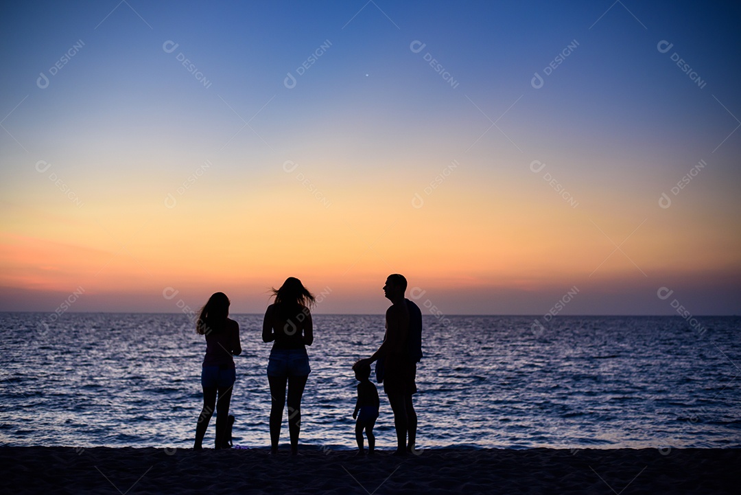 Família feliz na praia na hora do pôr do sol