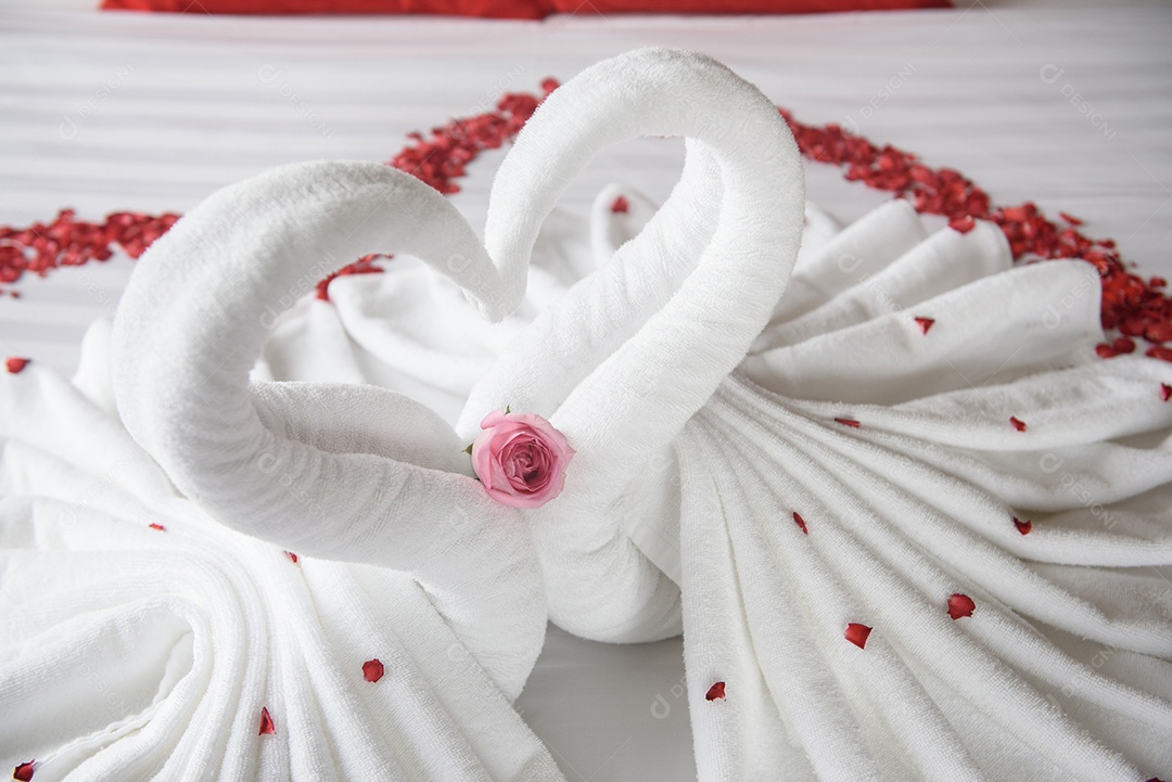 Dois cisnes e corações feitos de toalhas na cama de lua de mel