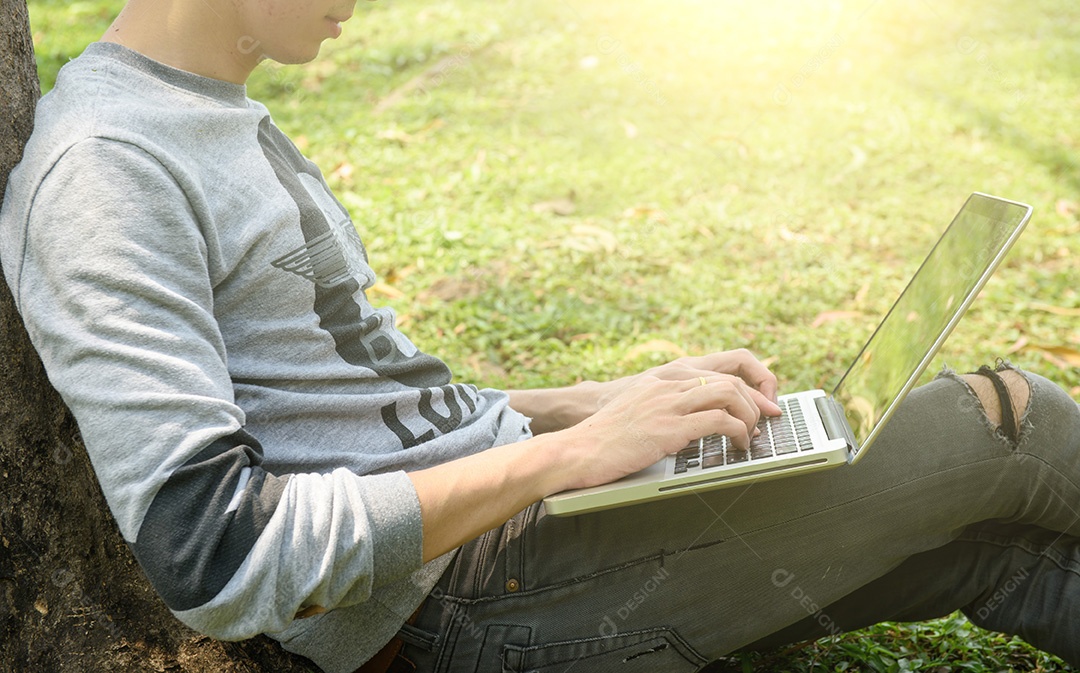 Jovem com telefone e laptop ao ar livre