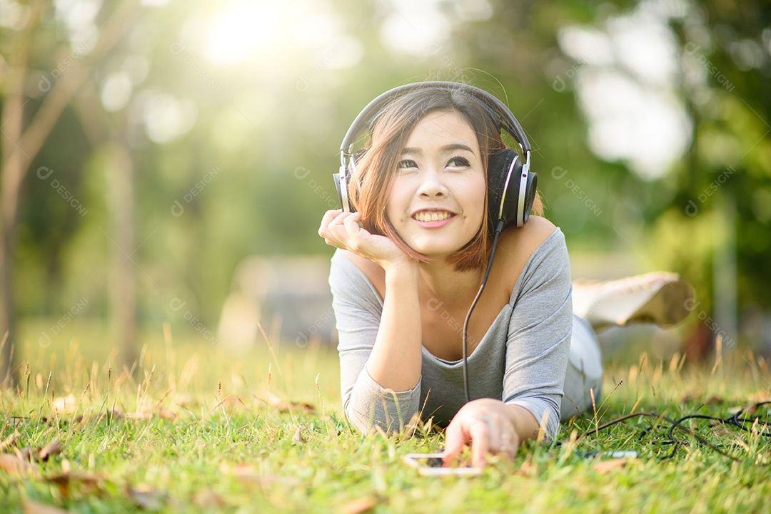 Jovem ouvindo música com fones de ouvido no parque da cidade