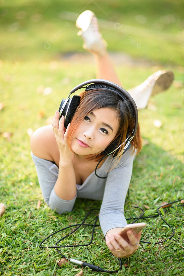 Jovem ouvindo música com fones de ouvido no parque da cidade