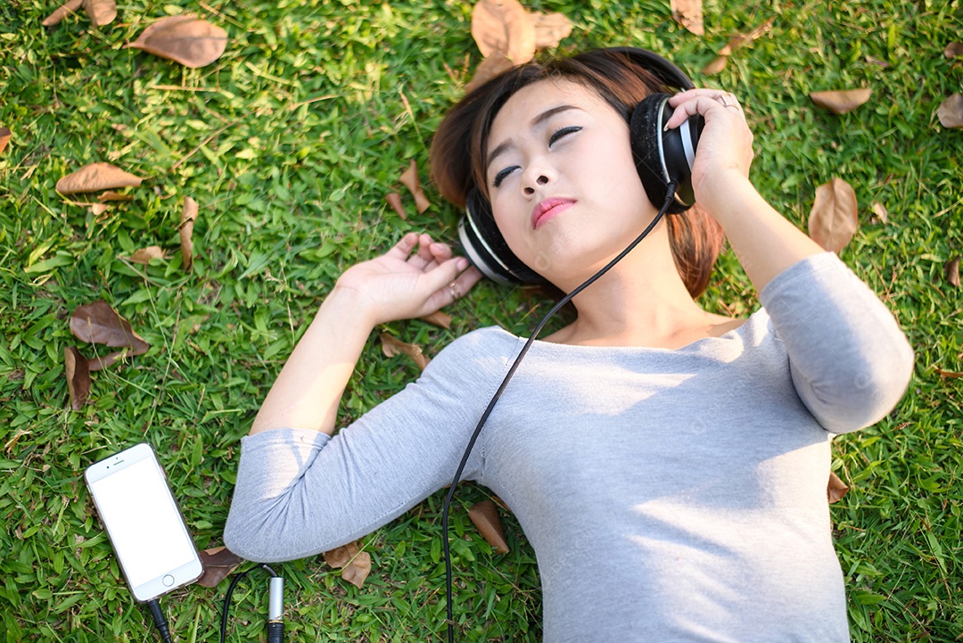 Jovem ouvindo música com fones de ouvido no parque da cidade