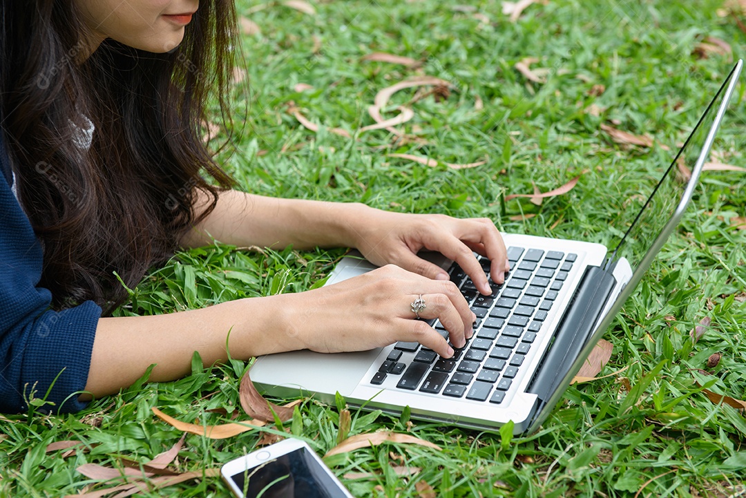 Garota de mão no teclado laptop em park city