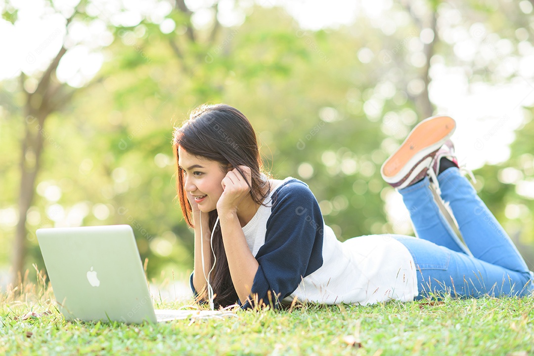 Jovem ouvindo música com laptop no parque da cidade