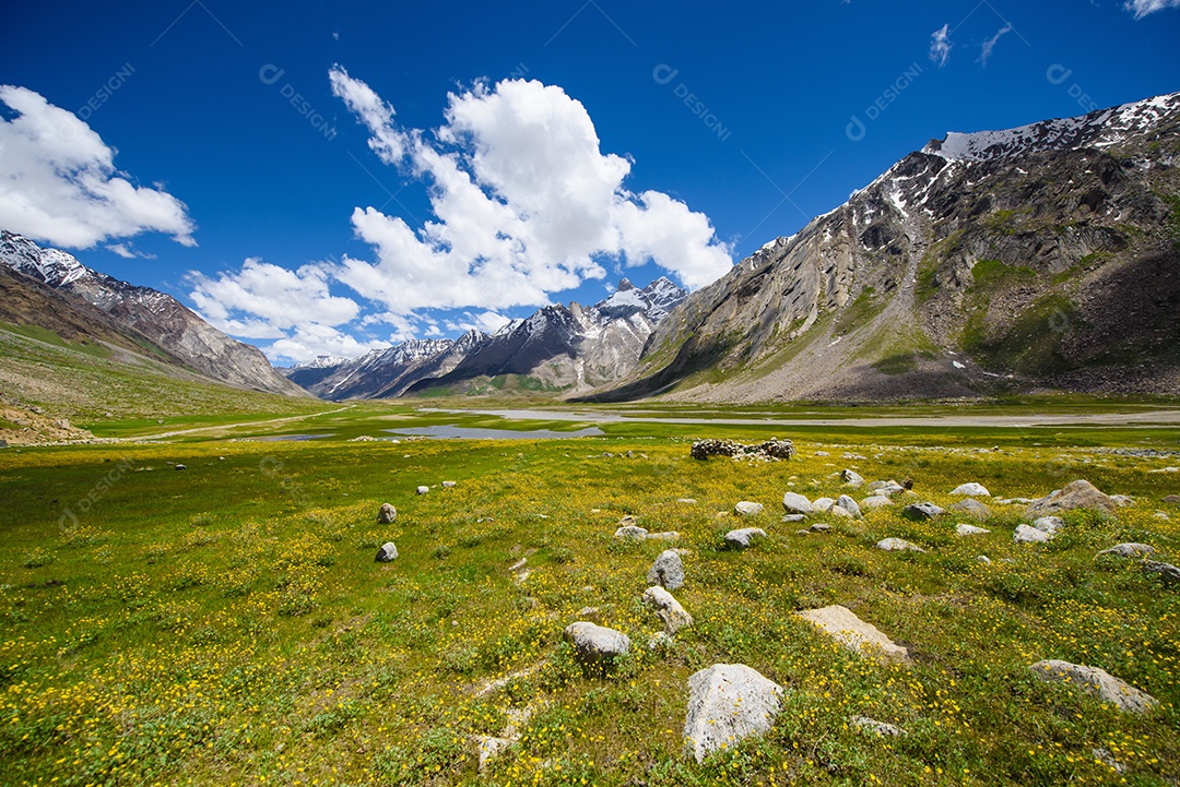 Campo nas montanhas com nuvens no céu azul