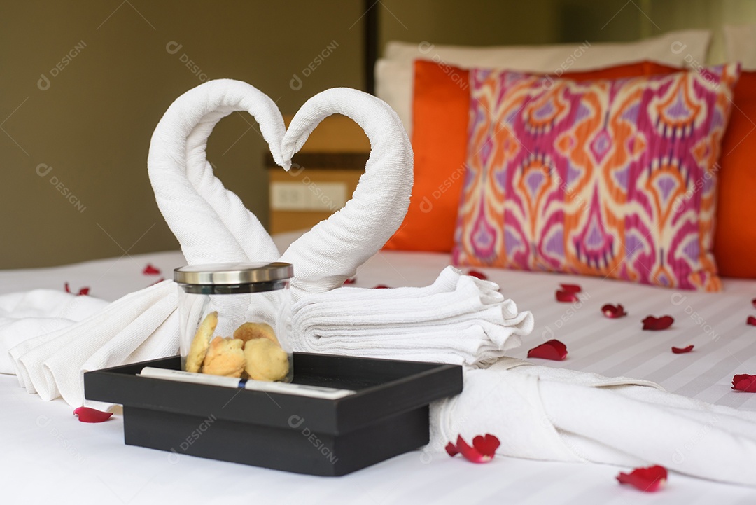 Dois cisnes e corações feitos de toalhas na cama de lua de mel