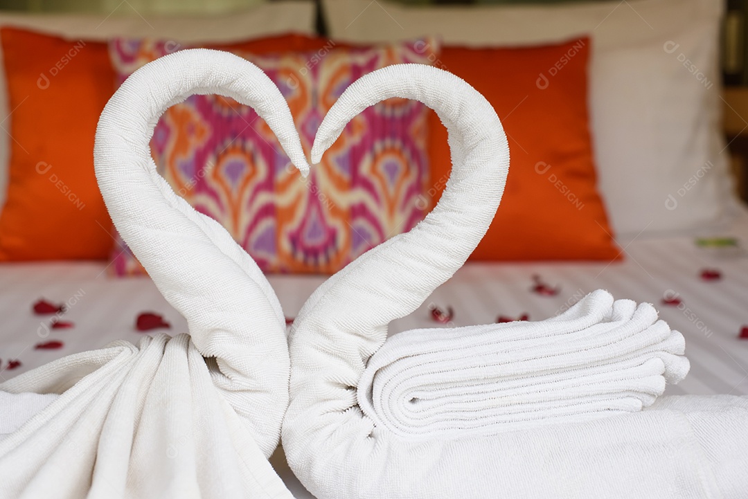 Dois cisnes e corações feitos de toalhas na cama de lua de mel
