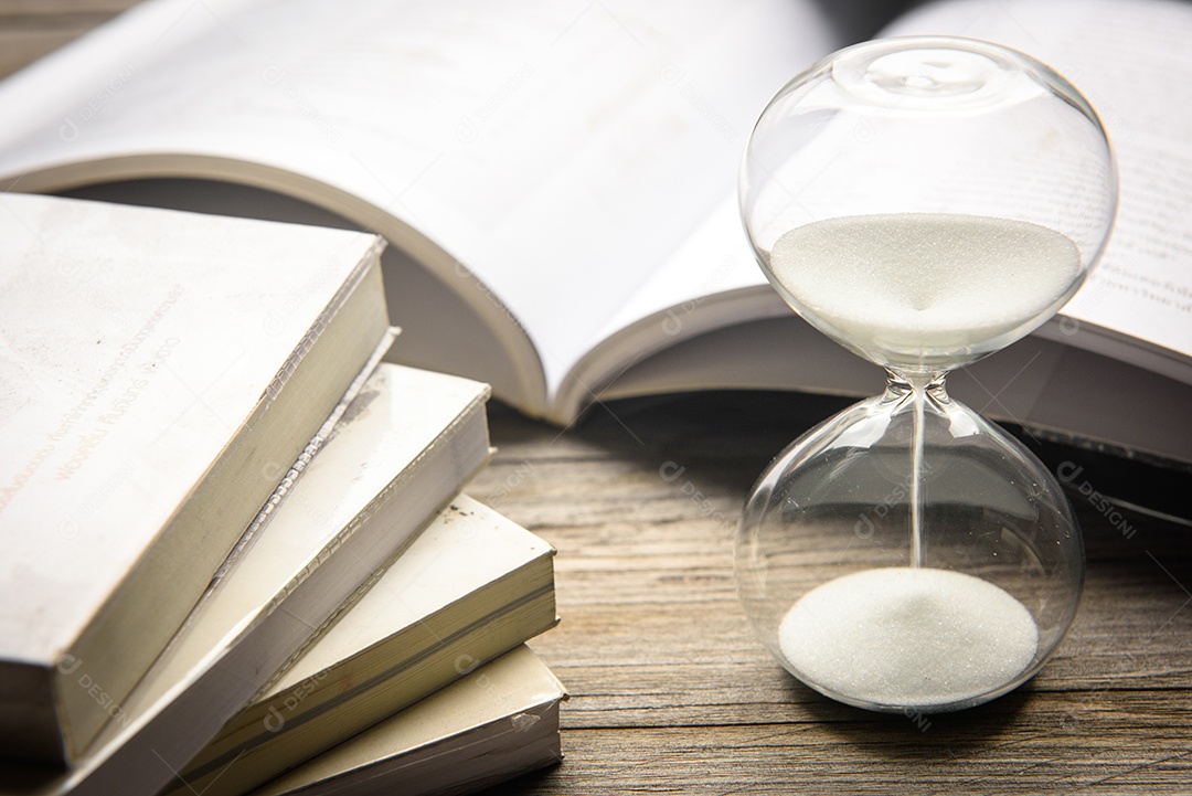 Ampulheta e livro aberto na mesa de madeira