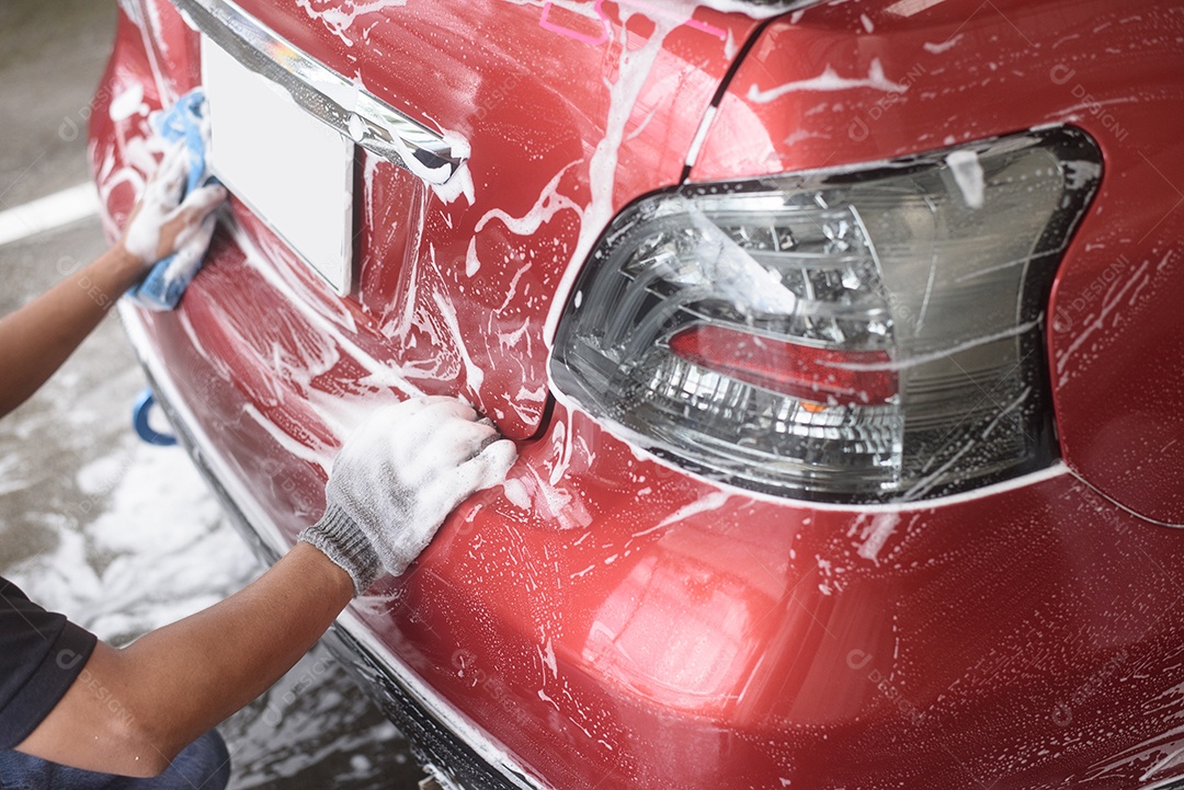 Mão segure a esponja sobre o carro para lavar