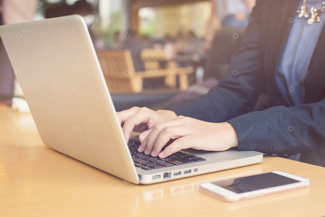 Mãos de uma mulher trabalhadora no teclado de seu laptop