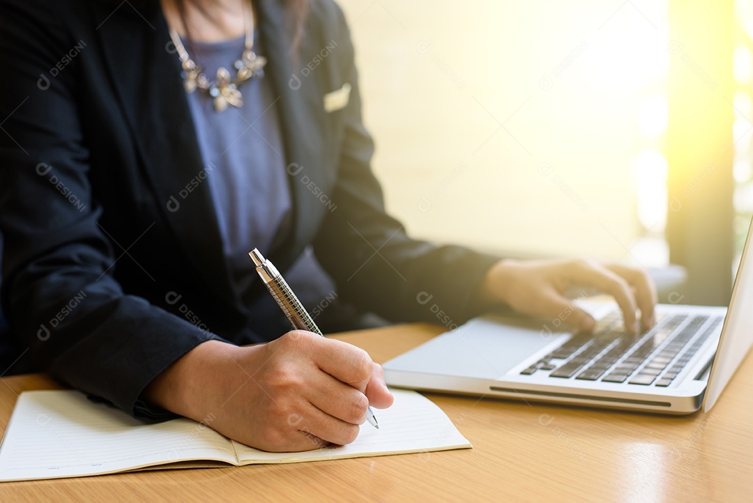 Imagem recortada de uma mulher trabalhando no laptop e escrevendo