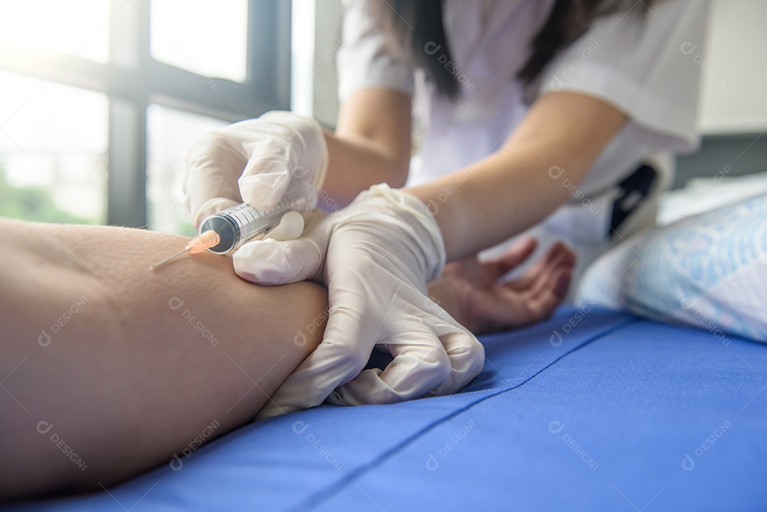 Médico fazendo injeção no joelho em seu escritório