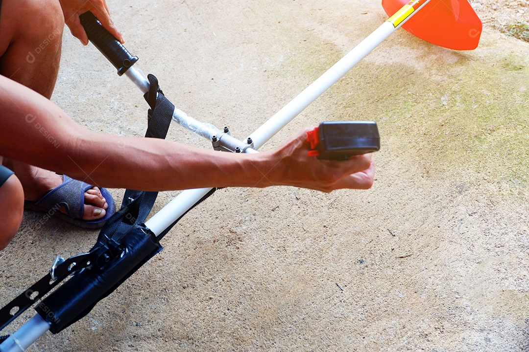 Mão do homem é segurar e apertar o botão Para fazer a lâmina de corte do cortador de grama é trabalho