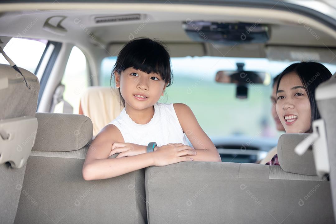 Menina feliz com família asiática sentada no carro para curtir a viagem e as férias de verão na van campista