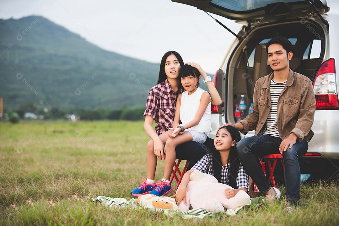 Menina feliz com família asiática sentada no carro para curtir a viagem e as férias de verão na van campista