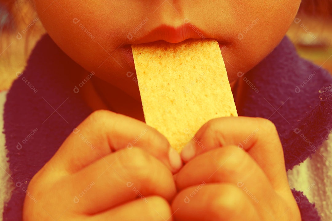 Garota está trazendo um lanche em sua boca.