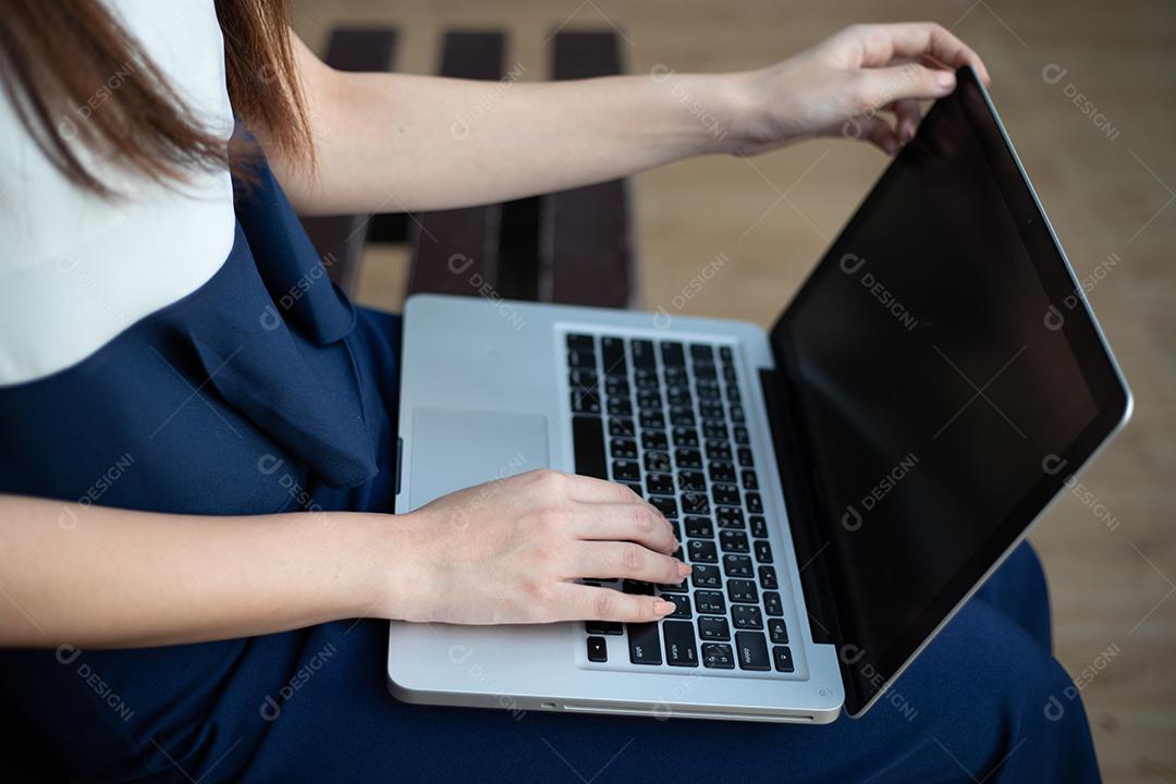 Mulheres de negócios asiáticos usando notebook e sorrindo felizes por trabalhar ao ar livre