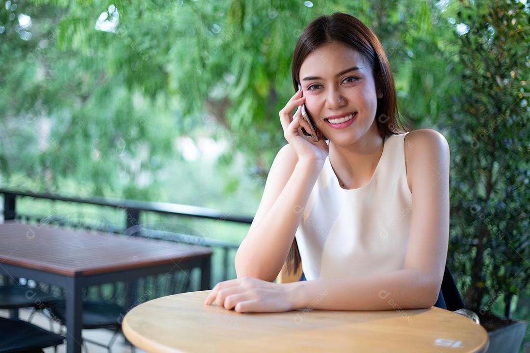 Empresários e mulheres da Ásia estão usando telefone inteligente móvel e sensível ao toque para comunicação e verificando pessoas de negócios no escritório