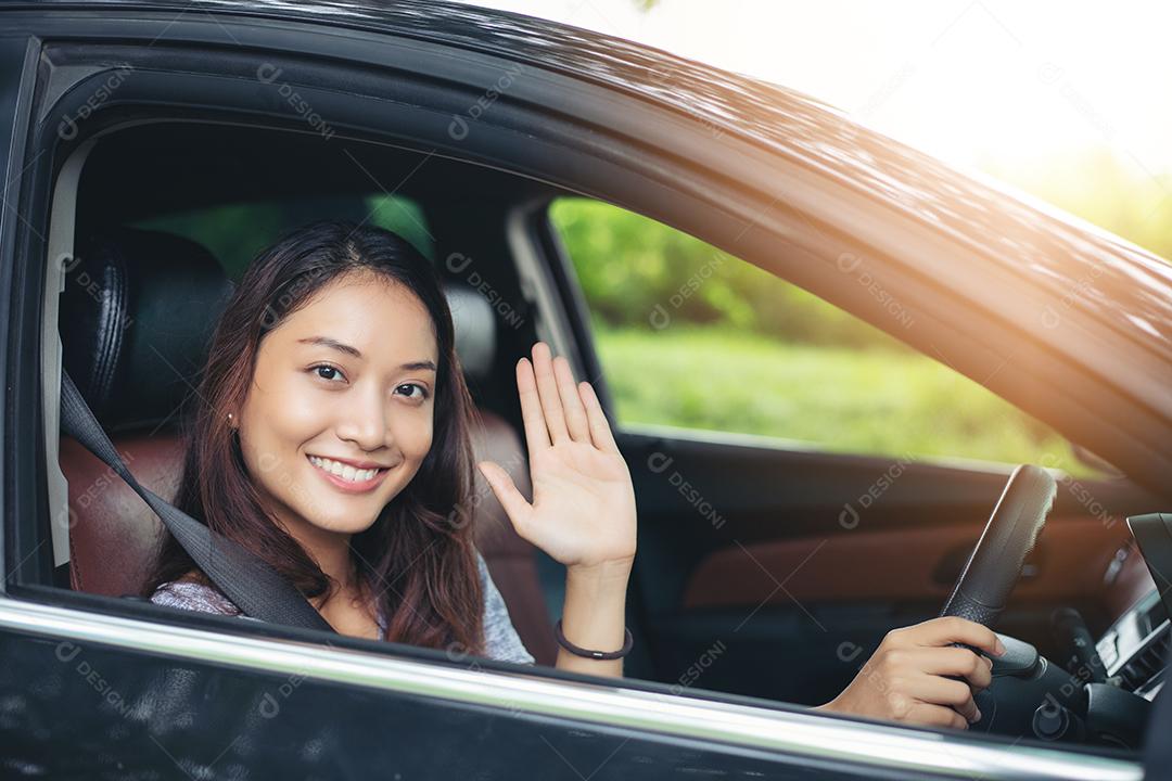 Linda mulher asiática sorrindo e gostando de dirigir um carro e a mão está prestes a entrar em marcha na estrada para viajar