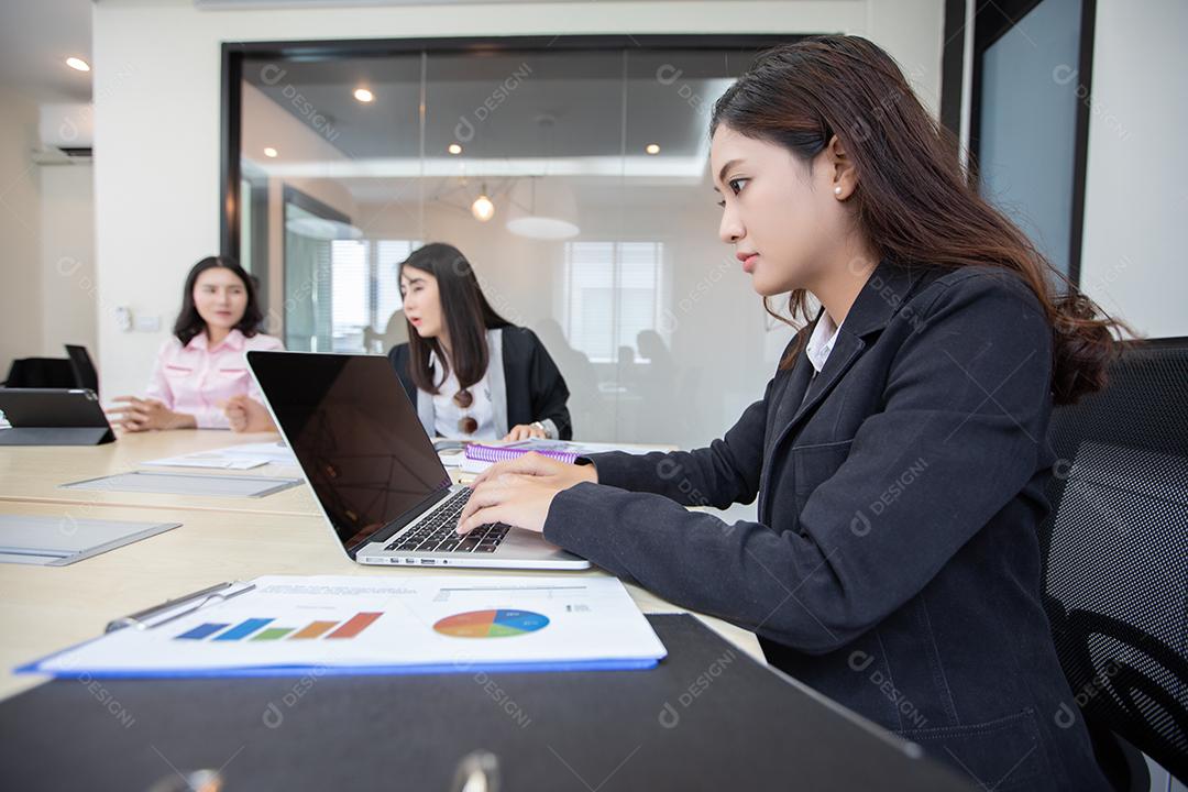 Empresária asiática séria sobre o trabalho e usando notebook para parceiros de negócios discutindo documentos e ideias na reunião