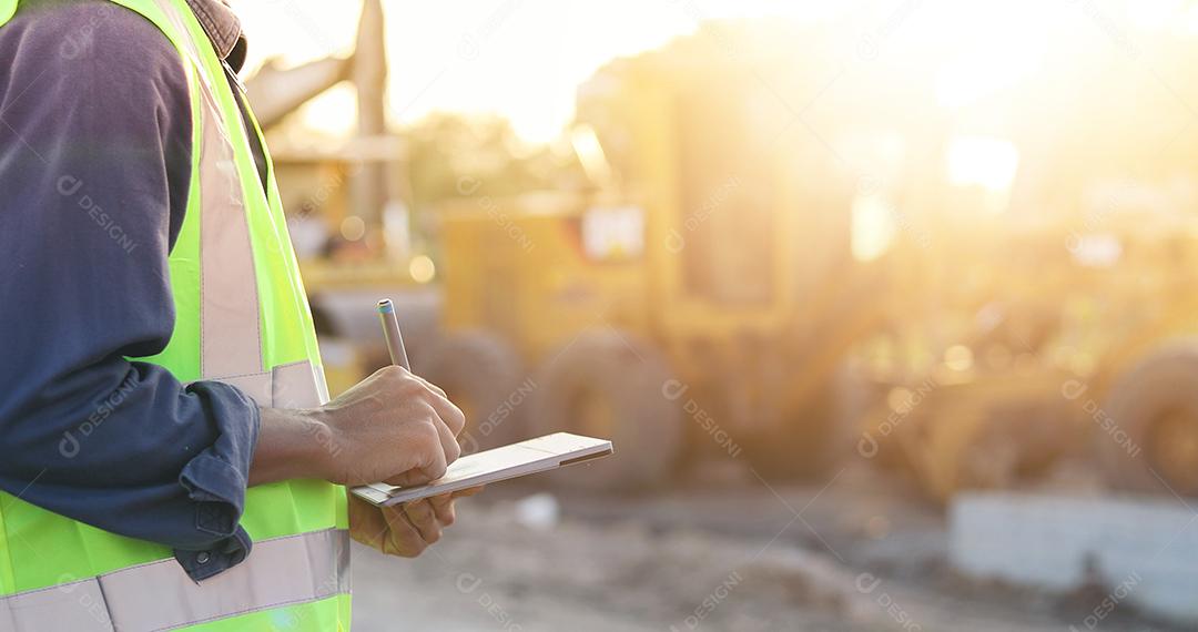 Engenheiro asiático com capacete usando computador tablet pc inspecionando e trabalhando no canteiro de obras