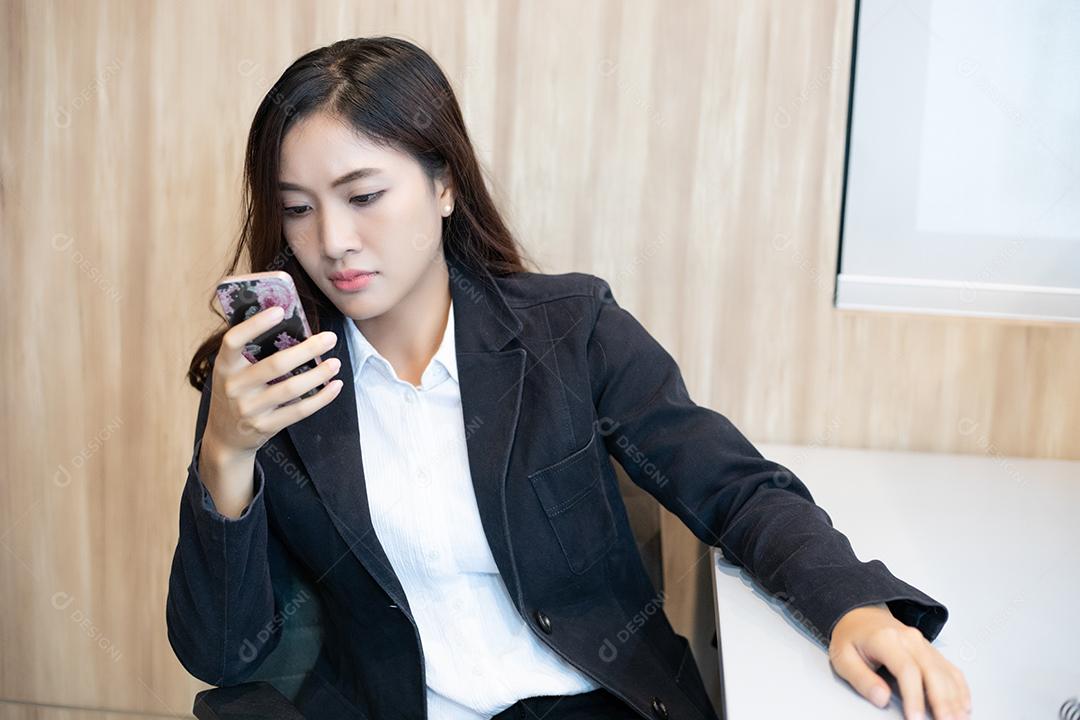 Mulher de negócios asiática usando telefone para celular e mensagens de texto em seu celular