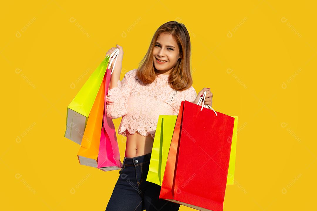 Mulheres asiáticas Linda garota está segurando sacolas de compras e sorrindo em fundo amarelo