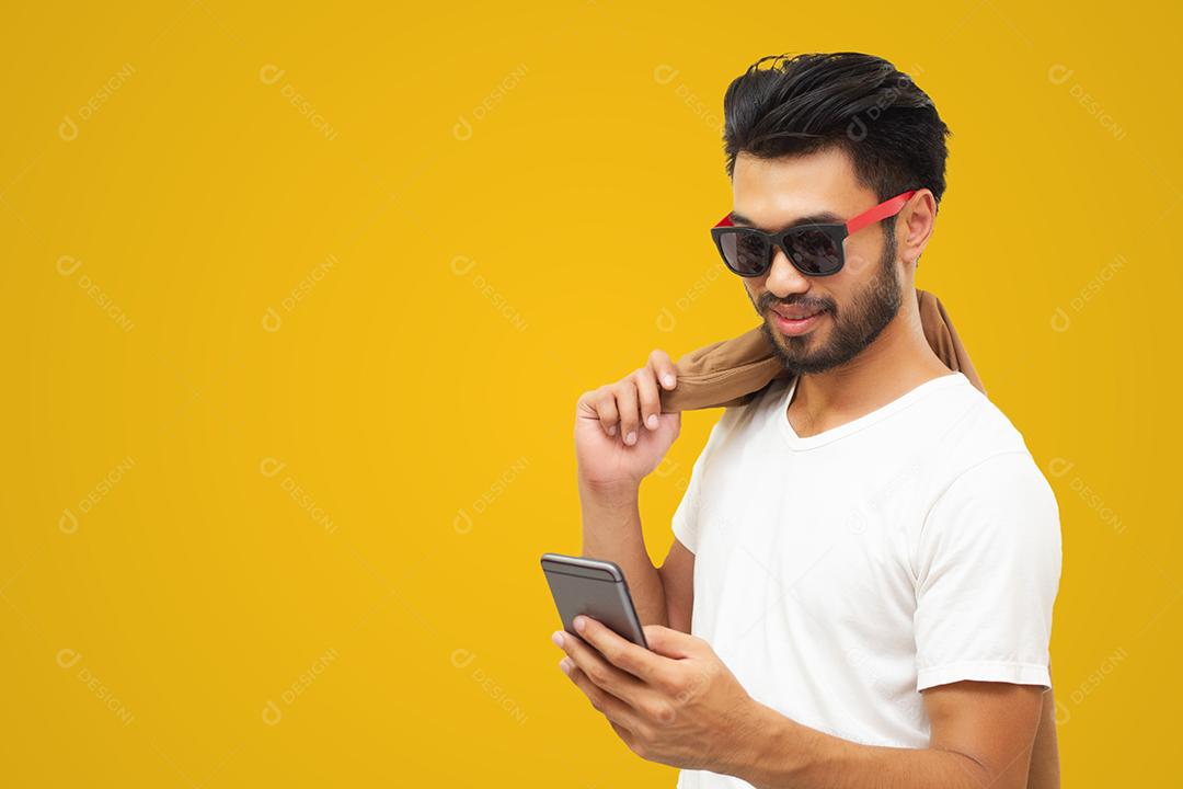 Homem de negócios asiáticos homem bonito com bigode, sorrindo e rindo e usando telefone inteligente em fundo amarelo