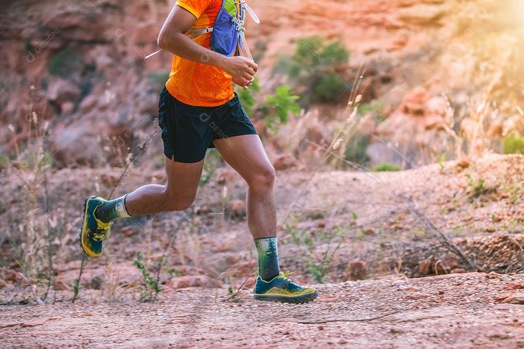 A male trail runner. and feet of an athlete wearing sports shoes for running in the mountains