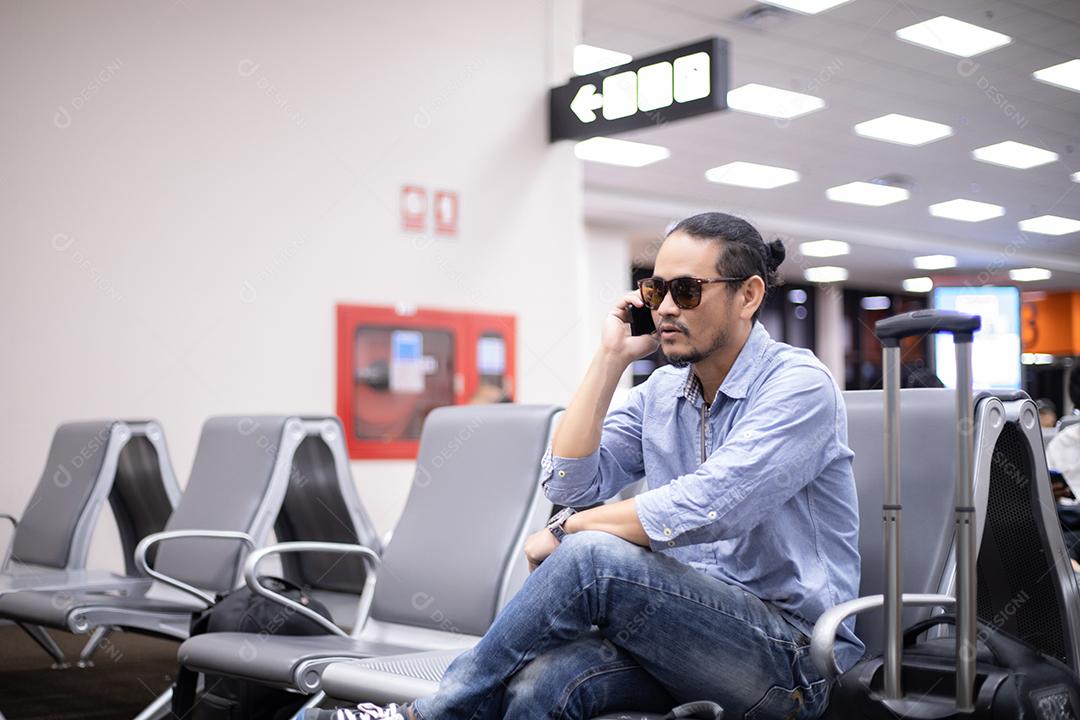 Homem asiático com viajante de mochila usando o celular inteligente para chamada de vídeo e levando em um aeroporto