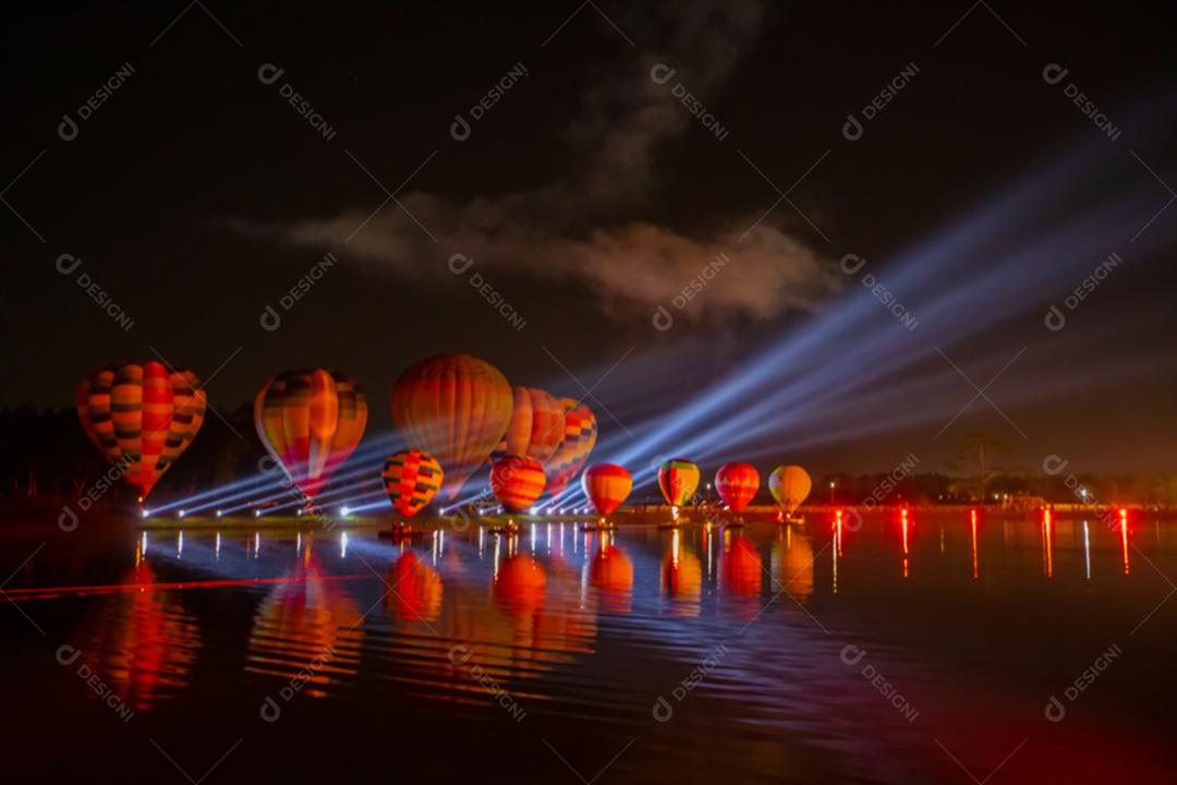 Balões de ar quente coloridos voando sobre o rio no festival noturno
