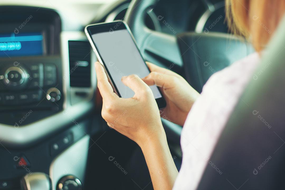 As mulheres asiáticas estão dirigindo carros e usando um smartphone na estrada.