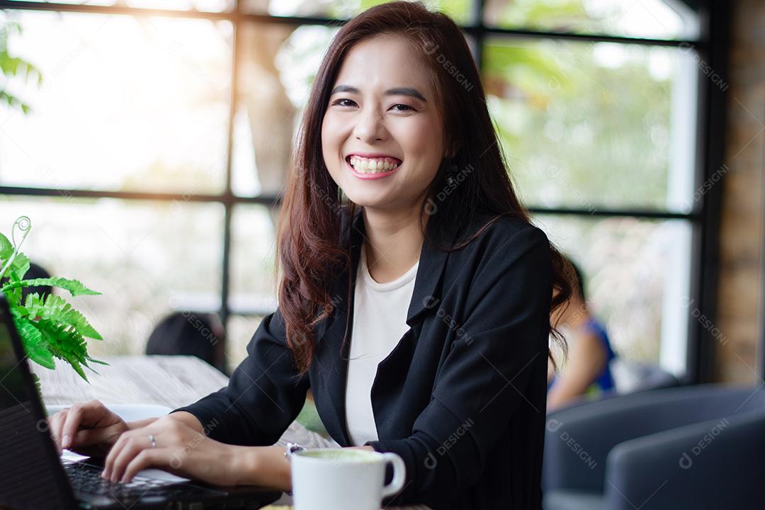 Mulheres de negócios asiáticos sorrindo e usando notebook para trabalhar no café