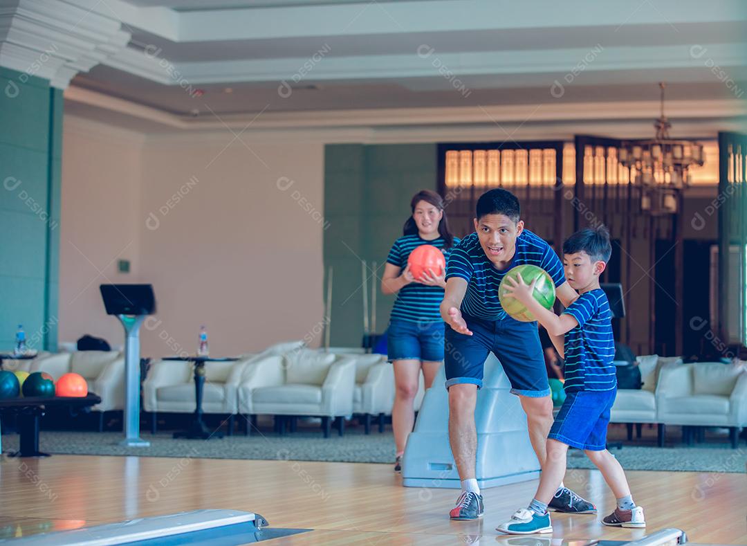 Pai ensinando filho e família a jogar boliche no clube de boliche na hora do relaxamento