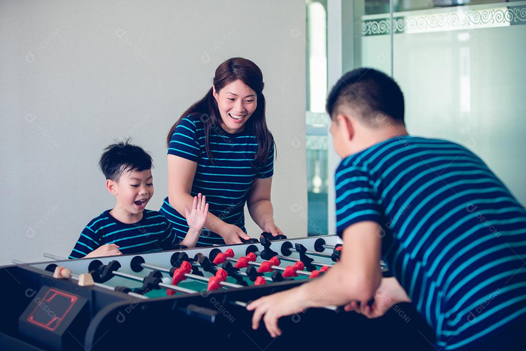 Família feliz jogando futebol de mesa para relaxar de férias em casa