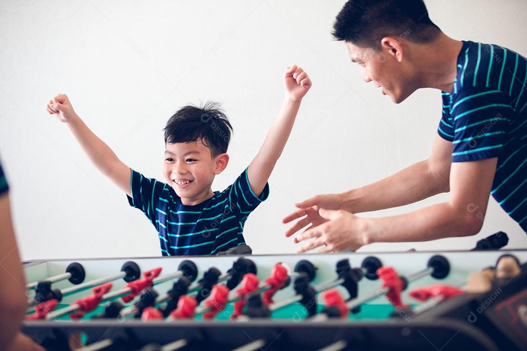 Família feliz jogando futebol de mesa para relaxar de férias em casa