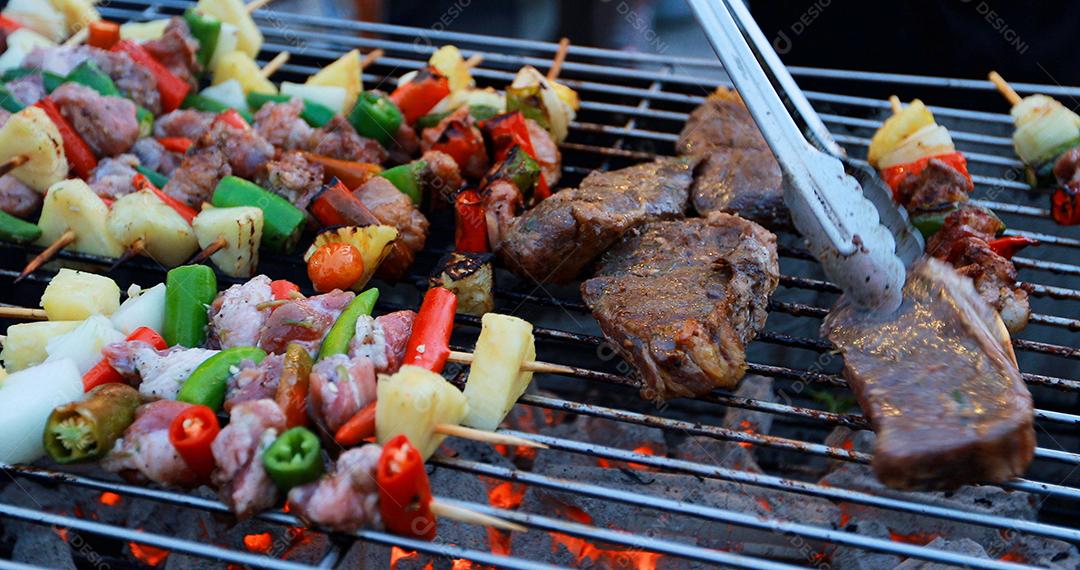 Grupo asiático de amigos fazendo churrasco de jardim ao ar livre rindo com bebidas alcoólicas de cerveja à noite