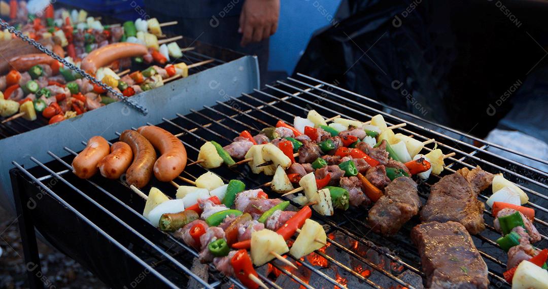 Grupo asiático de amigos fazendo churrasco de jardim ao ar livre rindo com bebidas alcoólicas de cerveja à noite