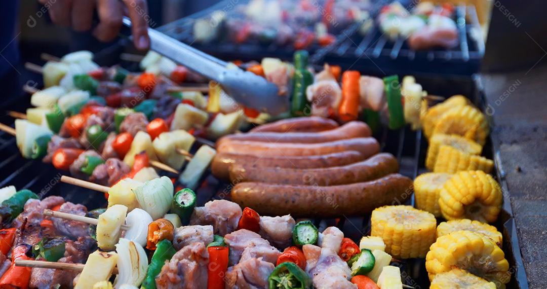 Grupo asiático de amigos fazendo churrasco de jardim ao ar livre rindo com bebidas alcoólicas de cerveja à noite