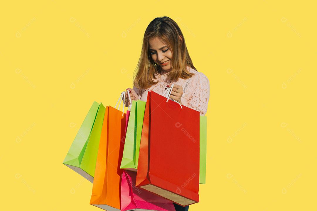 Mulheres asiáticas Linda garota está segurando sacolas de compras e sorrindo em fundo amarelo