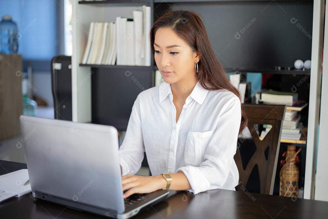 Mulheres de negócios asiáticos usando notebook e sorrindo felizes por trabalhar